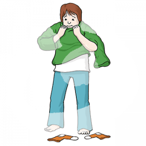 Ein Kind in Hose und T-Shirt zieht einen Pullover an. Vor den Füßen liegen Socken.