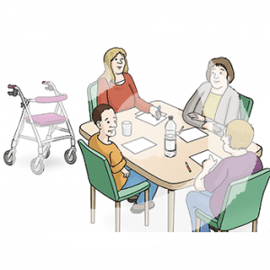 Vier Personen sitzen um einen Tisch herum. Vor jeder liegt ein Blatt und ein Stift. Im Hintergrund steht ein Rollator.