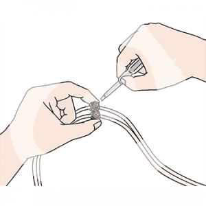 Eine Hand hält zwei Kabel mit Verbindungsklemmen. Die andere Hand hält einen kleinen Schraubenzieher.