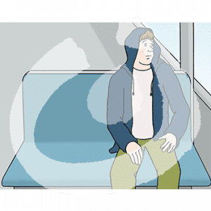 Eine ängstliche Person sitzt auf einer Bank in der Bahn und guckt aus dem Fenster.