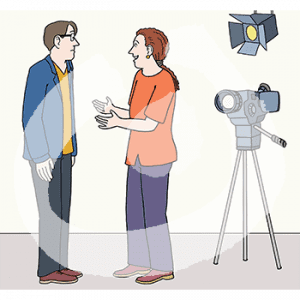 Zwei Personen stehen sich gegenüber. Dahinter steht eine Kamera und ein Scheinwerfer an der Wand.