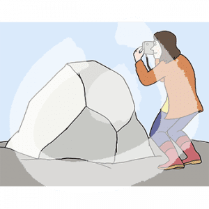 Eine Frau fotografiert mit einer Kamera einen großen Stein.