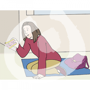 Eine Frau sitzt auf einer Decke und guckt ein Stück Papier an.