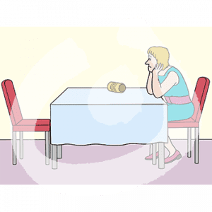 Eine traurige Frau sitzt mit in den Händen gestütztem Kopf an einem Tisch.