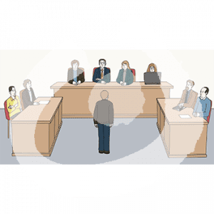 Vier Personen sitzen an einem Richtertisch. Links sitzen zwei Personen am Angeklagtentisch. Rechts sitzen zwei Personen am Staatsanwaltschaftstisch. In der Mitte steht eine Person.