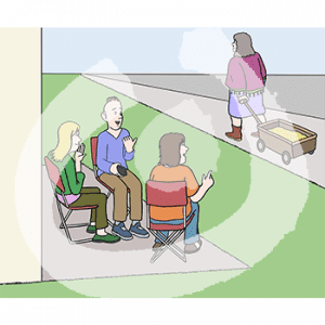 Drei Personen auf Stühlen sitzen nebeneinander vor einem Gebäude und gucken einer Person mit Bollerwagen hinterher.