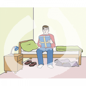 Ein Mann sitzt auf einem Bett. In den Händen hält er ein Geschenk.