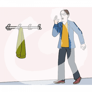 Ein Mann hält seine Hand neben seinen offenen Mund. Er steht neben einer Garderobe an der Wand.