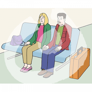 Ein Mann und eine Frau sitzen auf einer Bank. Neben ihnen steht ein Koffer.