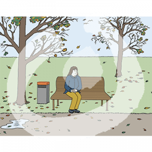 Eine Person sitzt auf einer Parkbank. Um sie herum liegen Blätter, die Bäume sind fast kahl.