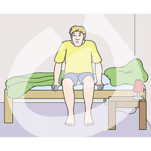 Eine Person sitzt auf einem Bett.