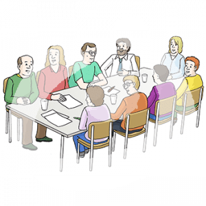 Neun Personen sitzen um einen Tisch herum. Vor jeder liegt ein Blatt und ein Stift.