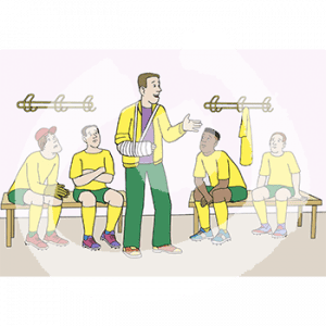 Ein Mann in gelbem Trainingsanzug und Gips Arm. Er steht zwischen vier Männern in gelben Trikots die auf Bänken sitzen.