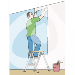 Eine Person steht auf einem Tritt und hält eine Tapetenbahn in den Händen. Ein Teil der Wand ist tapeziert. Auf dem Boden steht ein Eimer mit Tapetenpinsel.