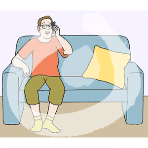 Eine Person sitzt auf einem Sofa und hält sich ein Handy ans Ohr.