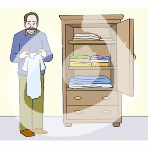 Eine Person hält ein Shirt in der Hand. Sie steht neben einem offenen Kleiderschrank mit gefalteter Wäsche.