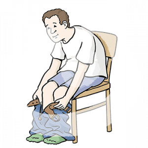 Eine Person sitzt in T-Shirt und Unterhose auf einem Stuhl. Die Hose hängt an den Füßen.