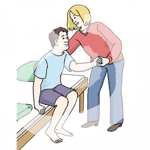 Eine Person sitzt auf einer Bettkante. Eine andere Person umfasst ihren Rücken und hält eine Hand.