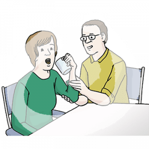 Zwei Personen sitzen an einem Tisch. Eine Person hat einen offenen Mund und einen Becher in der Hand. Die andere Person hält ihren Arm und Ellenbogen fest.