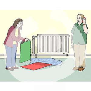 Zwei Personen stehen vor einer Heizung mit einer Wasserpfütze. Eine Person legt Tücher auf die Pfütze, die andere hat ein Handy am Ohr.