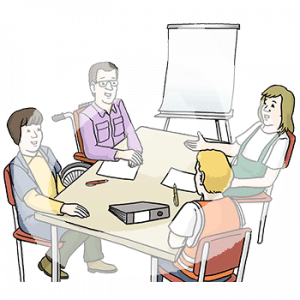 Vier Personen sitzen um einen Tisch herum. Vor jeder liegt ein Blatt und ein Stift. Eine Person sitzt im Rollstuhl. Im Hintergrund ist ein Flipchart.