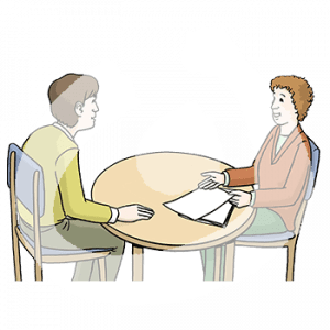 Ein Mann und eine Frau mit heller Hautfarbe sitzen an einem Tisch. Die Frau zeigt auf zwei Zettel.