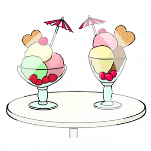 Zwei Becher mit Eiskugeln, Waffeln und Schirmchen stehen auf einem Tisch.