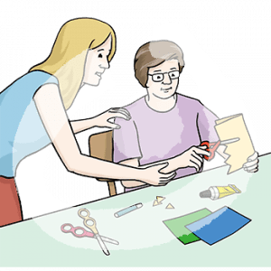 Eine Person schneidet Zickzackmuster in ein Papier. Auf dem Tisch liegen bunte Blätter, Klebe, eine Schere und ein Stift. Eine Person steht neben ihr und führt ihren Arm.