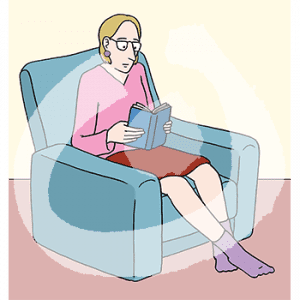 Eine Frau sitzt lesend in einem Sessel.