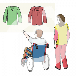 Eine Person im Rollstuhl zeigt auf eins von zwei Oberteilen. Daneben steht eine weitere Person.