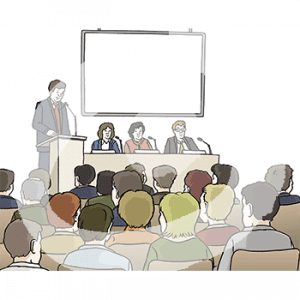 Personen in Stuhlreihen gucken auf eine Bühne. Dort sitzen drei Personen mit Mikros an einem Pult. Daneben steht eine Person an einem Rednerpult.