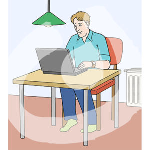 Eine Person sitzt in Socken mit einem Laptop an einem Tisch. Im Hintergrund ist eine Heizung.