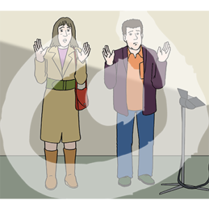 Zwei ängstliche Personen stehen mit erhobenen Händen vor einer Wand.