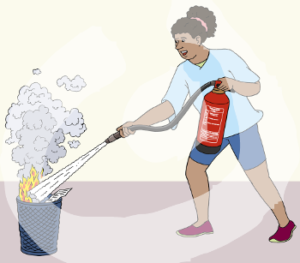 Eine Frau hat einen Feuerlöscher in der Hand und sprüht damit auf einen brennenden Papierkorb.