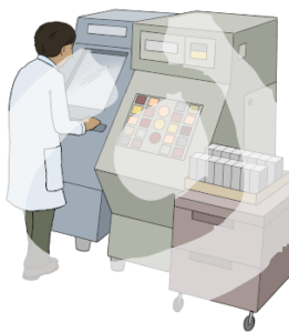 Eine Person steht vor einer Maschine und guckt durch eine Scheibe. Daneben steht eine weitere Maschine mit Knöpfen, daneben ein Rollwagen.