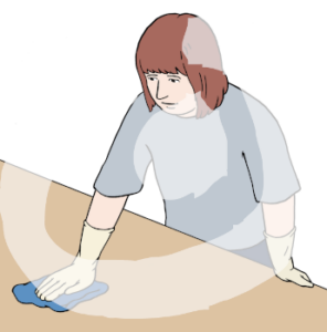 Eine Person steht abgestützt mit einem Lappen vor einem Tisch. Sie wischt den Tisch.