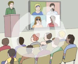 Einige Menschen sitzen vor einer Bühne im Publikum. Auf der Bühne steht eine Person an einem Rednerpult. Neben ihr ist ein großer Bildschirm mit vier Gesichtern.