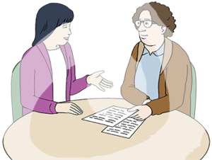 Eine Frau und ein Mann sitzen an einem Tisch. Die Frau ist asiatisch gelesen. Der Mann hat eine helle Hautfarbe. Der Mann hält einen Zettel in der Hand und schaut die Frau an.